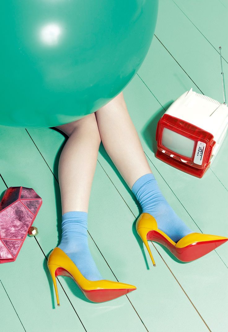 Yellow patent heels with blue socks on mint floor — playful complementary