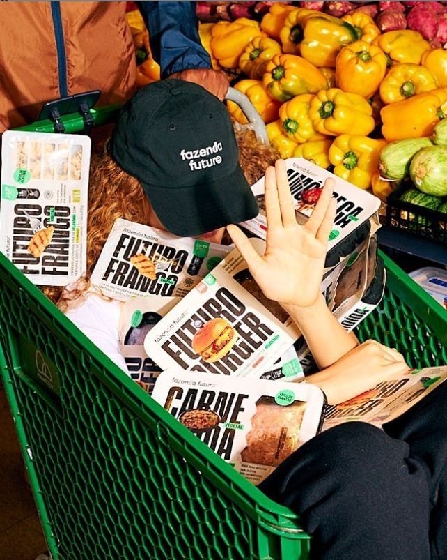 Hand reaching into a green cart overflowing with Fazenda Futuro products — haul-reveal energy