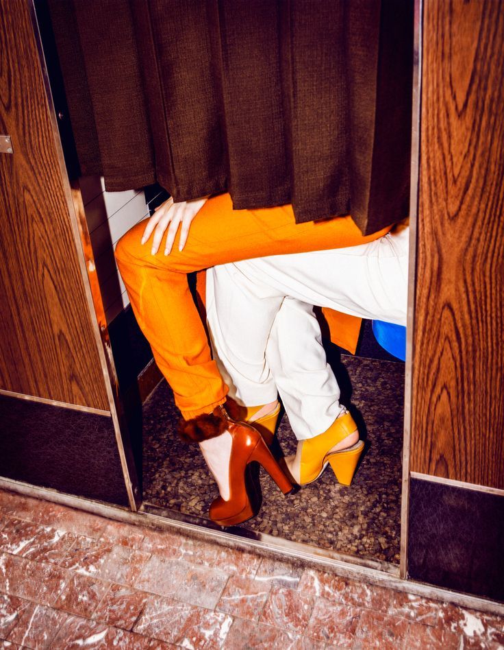 Orange and yellow heels peeking from behind a dressing-room curtain