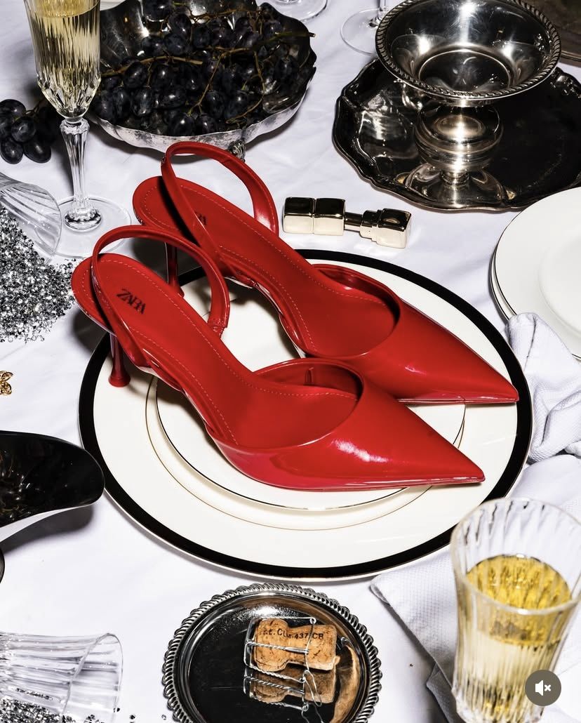 Red heels plated overhead at a dinner setting — editorial flat-lay